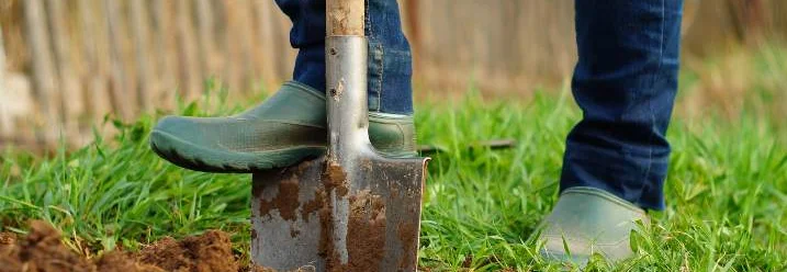 Person gräbt mit Spaten Erde um